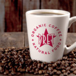 Pret a Manger logo on a coffe cup sitting on top of coffee beans