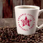 Pret a Manger logo on a coffe cup sitting on top of coffee beans
