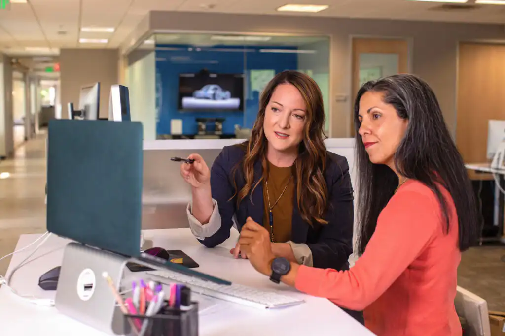 Two women looking at a computer screen in the office discussing what they see