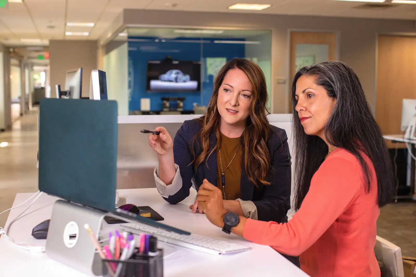 Two women looking at a computer screen in the office discussing what they see