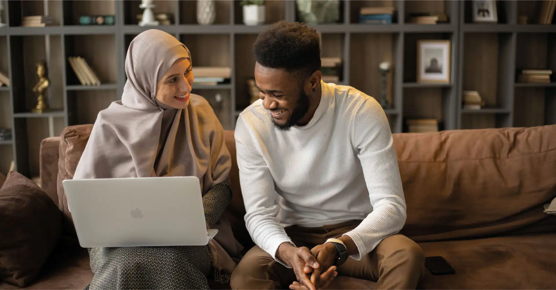 A man and a woman looking at research material on a laptop
