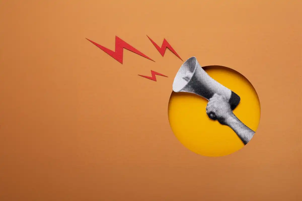 A paper-cut art style illustration of a hand holding a megaphone with red lightning bolts, representing powerful communication to overcome market research challenges
