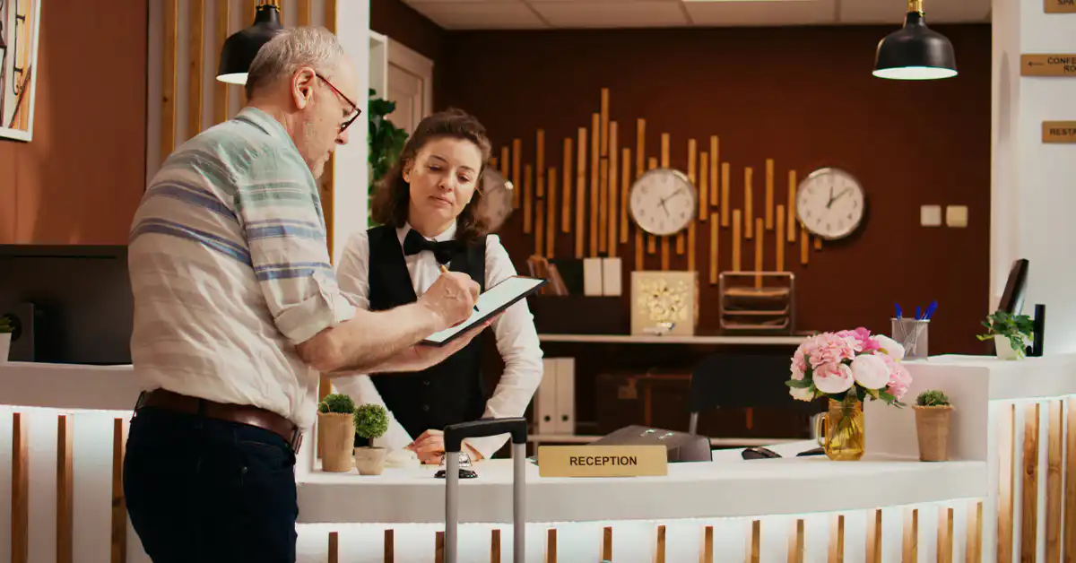 A receptionist and a customer reviewing a guest experience form on a tablet device.