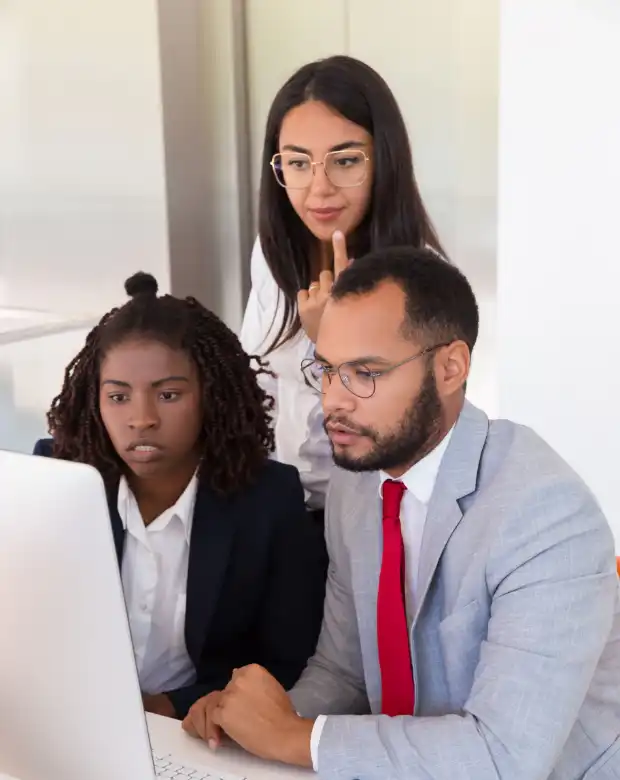 Focused colleagues reviewing data on a computer screen, symbolizing Vietnamese language solutions